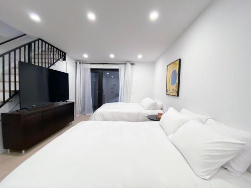 a white bedroom with two beds and a flat screen tv at Private Garden Two Bedroom Residence in Luxury Condominium in New York