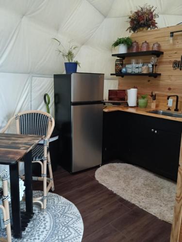 a kitchen with a refrigerator and a table in a tent at WATERFRONT LUXURY GLAMPING DOME in Rogersville