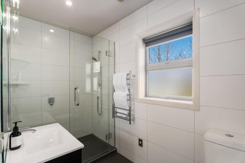 a white bathroom with a sink and a window at Kinsale - Spa, Pool, Gym and Tennis! in Arrowtown