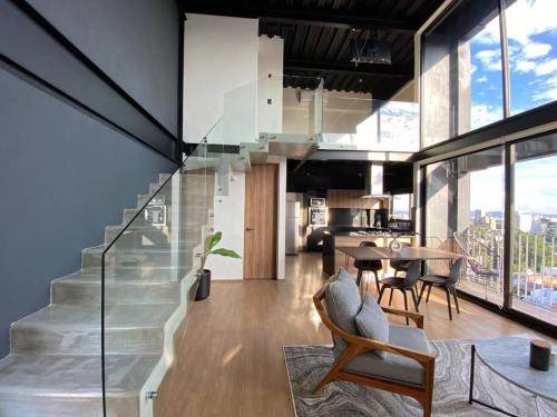 a living room with a staircase and a table and chairs at Loft Doble Altura Americana Piso 5 @serra in Guadalajara