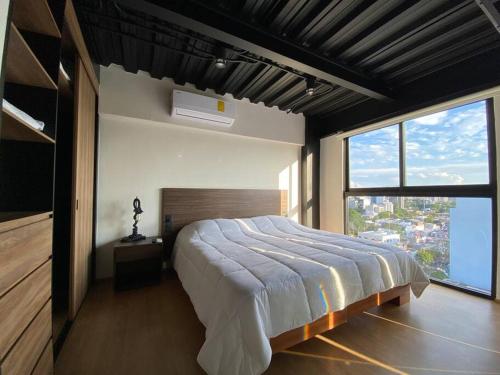 a bedroom with a large bed and a large window at Loft Doble Altura Americana Piso 5 @serra in Guadalajara
