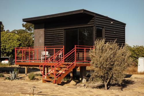 une petite cabine avec une balustrade rouge en face de celle-ci dans l'établissement Villas Quijote Valle de Guadalupe, à Bonito