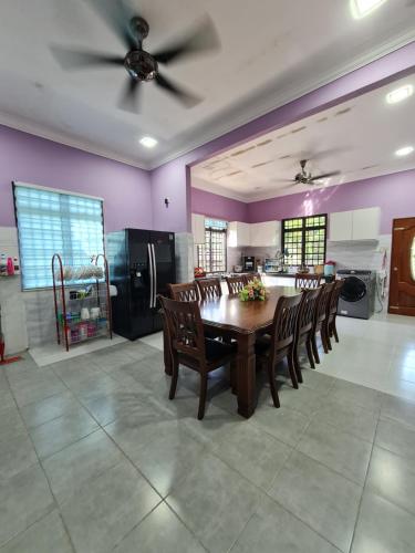 d'une salle à manger avec une table, des chaises et des murs violets. dans l'établissement Homestay Nukman Bukit Besi, à Dungun