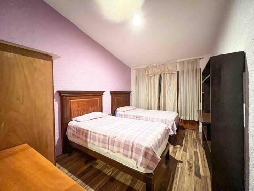 Habitación con 2 camas, paredes de color rosa y suelo de madera. en Casa cerca de Andares, Amplia / Planta Baja @serra, en Guadalajara