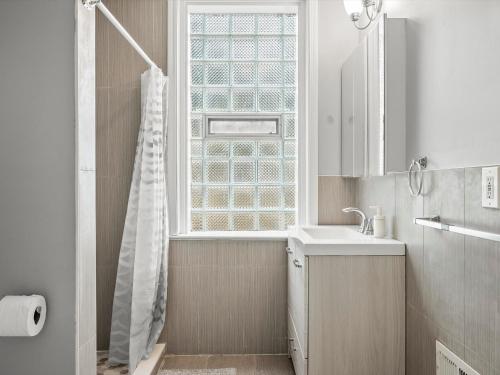 uma casa de banho com um chuveiro, um lavatório e uma janela em Oakland/University @A Spacious & Modern Private Bedroom with Shared Bathroom em Pittsburgh