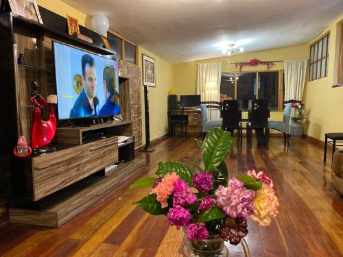 a living room with a flat screen tv and flowers at MY WAY Apartment in Cusco