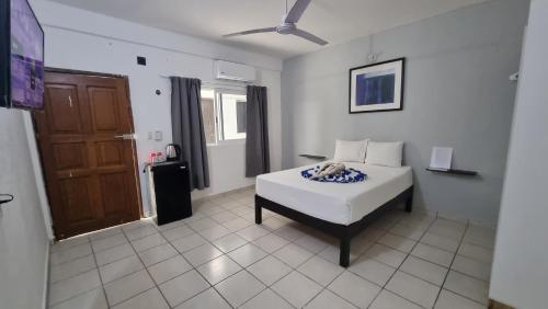 um quarto com uma cama branca e uma porta castanha em Casa Maria Fernanda em Playa del Carmen