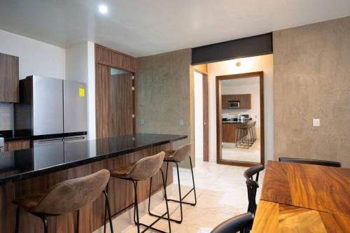 uma cozinha com um bar com cadeiras e uma mesa em Best Location Americana @serra em Guadalajara