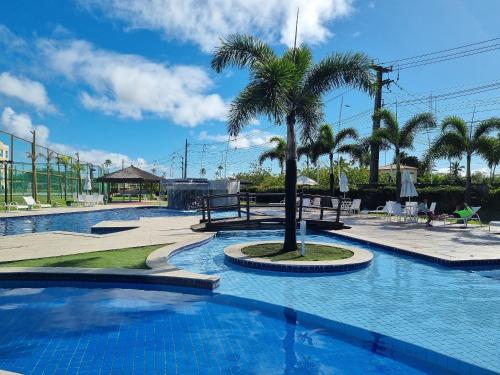 a swimming pool with a palm tree in the middle at Muro Alto Condomínio Clube Porto de Galinhas por Brevelar in Porto De Galinhas