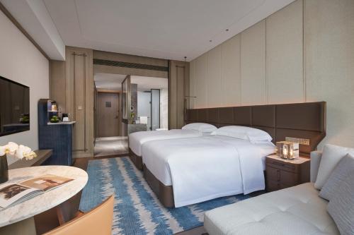 a hotel room with two beds and a couch at InterContinental Hotels Zhengzhou in Zhengzhou