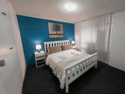 a bedroom with a white bed and a blue wall at Glenelg Air B & B in Glenelg