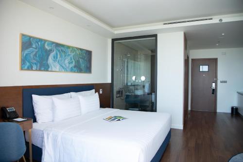 a hotel room with a white bed and a phone at FLC Grand Hotel Quy Nhon in Quy Nhon