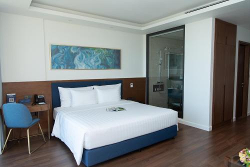 a bedroom with a white bed and a glass shower at FLC Grand Hotel Quy Nhon in Quy Nhon
