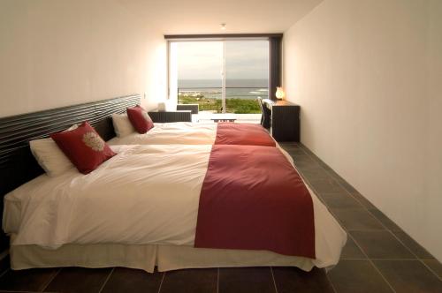 sypialnia z dużym łóżkiem i dużym oknem w obiekcie Private Resort Hotel RENN w mieście Miyako-jima