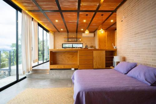 1 dormitorio con 1 cama de color púrpura en una habitación con ventanas en Estudio, vista increíble @serra, en San Juan Cosalá