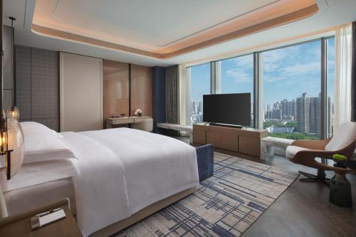 InterContinental Hotels Zhengzhou في تشنغتشو: غرفة فندق بسرير كبير وتلفزيون
