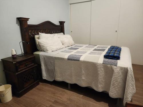 ein Bett mit einer blauen und weißen Decke und einem Nachttisch in der Unterkunft Apartamento Granat cerca del aeropuerto y la zona cultural y gastronómica in Guatemala