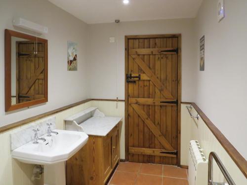 a bathroom with a sink and a wooden door at 5 Swallowholm Cottages in Richmond