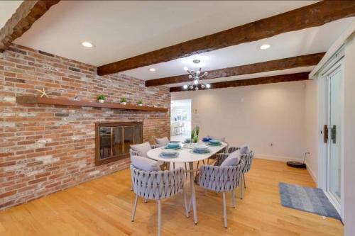 a dining room with a brick wall and a table and chairs at Cape Cod Home w/Ocean View, Roof Top, Pool & Hot Tub in Wellfleet