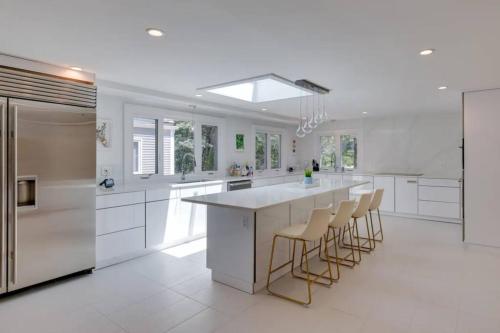 a white kitchen with a large island with bar stools at Cape Cod Home w/Ocean View, Roof Top, Pool & Hot Tub in Wellfleet