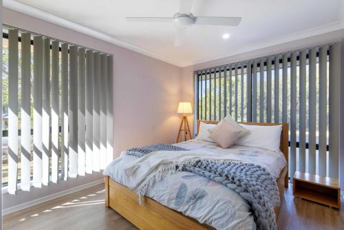 a bedroom with a bed and large windows at Hinterland Breakfast Deal - First night! in Beerwah