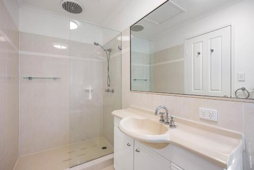a white bathroom with a sink and a shower at Terrapin Apartments in Noosaville