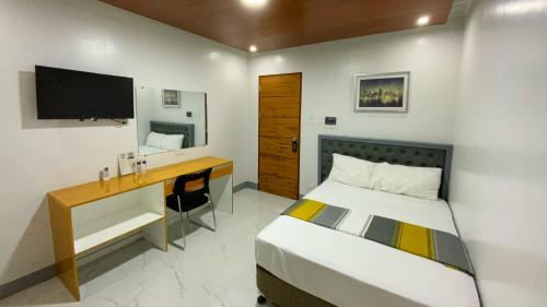 een slaapkamer met een bed, een bureau en een televisie bij ICON Venue and Suites in General Santos
