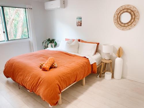 una camera da letto con un letto con una coperta arancione di Cosy Home Byron Bay a Byron Bay