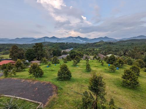 a field with trees and mountains in the distance at Villa with Titiwangsa Hill View in Kerling