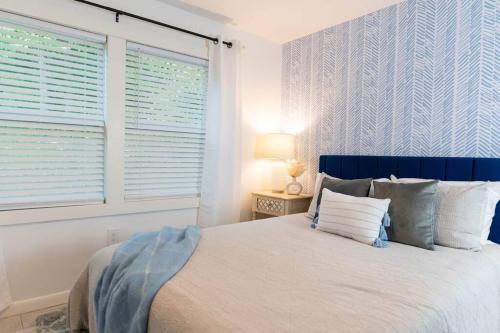 a bedroom with a bed with a blue headboard and windows at Parker House - 15 mins to Downtown Asheville in Fairview