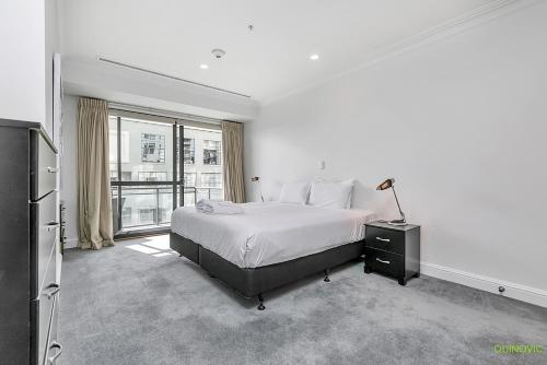 a white bedroom with a bed and a large window at QV Private City Hub Apartment - 484 in Auckland