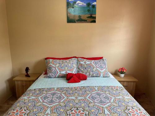 een bed met twee kussens en een rode knuffel erop bij La Caille Créole in Roseau