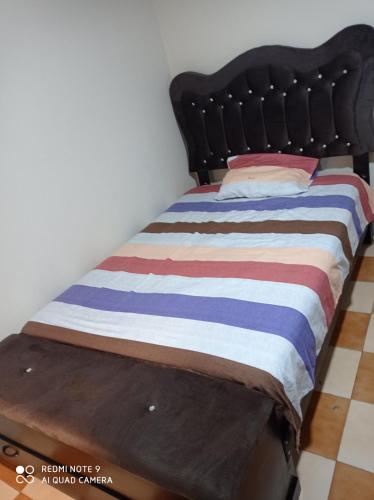 een bed met een houten frame en een gestreepte deken bij Mardry in Trujillo