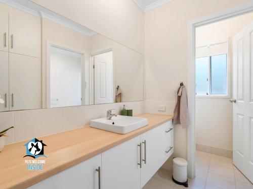 a white bathroom with a sink and a mirror at Sweeping Ocean Views 4BR on One Acre in Encounter Bay