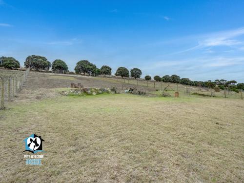 an empty field with a fence and trees in the background at Sweeping Ocean Views 4BR on One Acre in Encounter Bay
