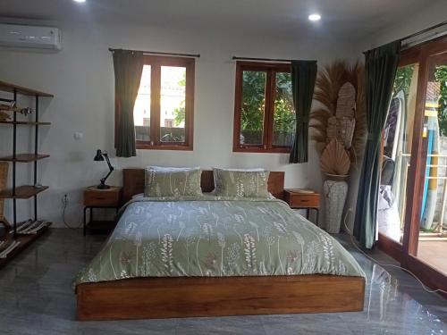 a bedroom with a large bed and windows at Hideaway Batukaras in Pangandaran