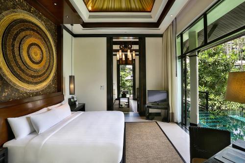a bedroom with a bed and a desk and a television at Banyan Tree Samui in Lamai
