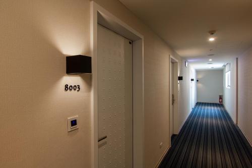 a hallway with a door with a sign on it at CHECK inn New Taipei LuZhou in Taipei
