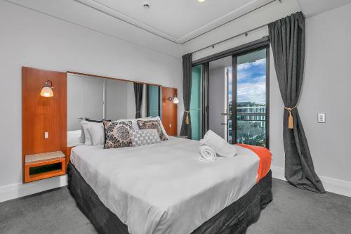 - une chambre avec un grand lit et une grande fenêtre dans l'établissement Bachelor's Sunset Pad, à Auckland