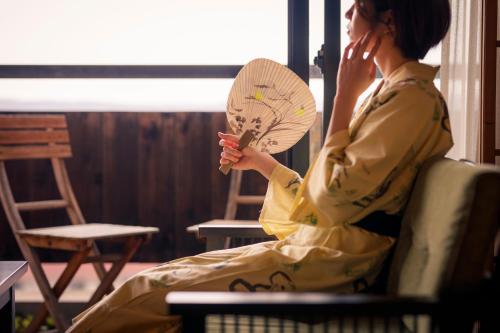 a woman sitting in a chair holding a fan at Hatori in Kaga