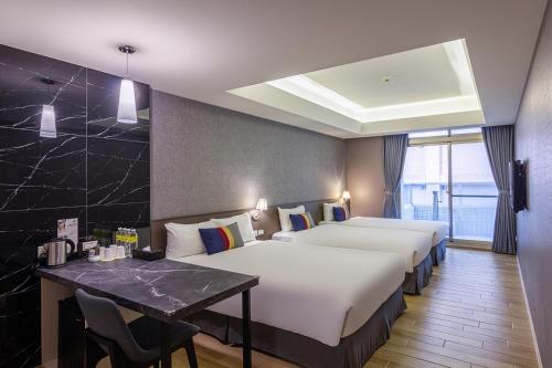 a hotel room with two beds and a table at CHECK inn New Taipei LuZhou in Taipei