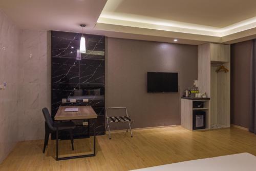 a living room with a table and a television at CHECK inn New Taipei LuZhou in Taipei