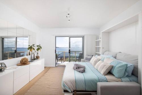 a bedroom with a bed and a kitchen with windows at Blue Vista in Nelson Bay