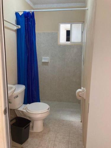 a bathroom with a toilet and a blue shower curtain at Departamento en Pomoca in Palenque