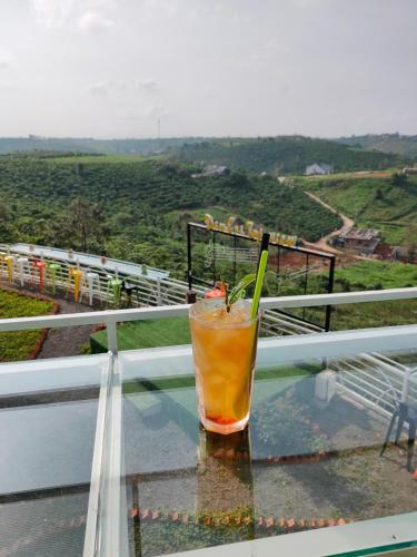 a drink sitting on a glass table on a balcony at Đamb'ri Top View Farmstay & Glamping in Bao Loc