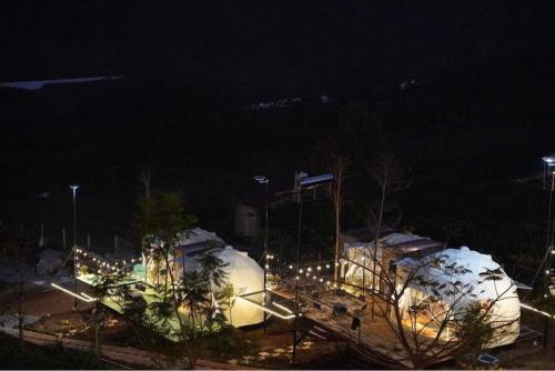 un groupe de dômes couverts de lumière la nuit dans l'établissement Đamb'ri Top View Farmstay & Glamping, à Bảo Lộc