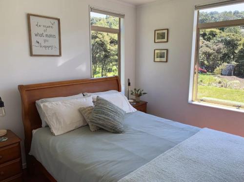 1 dormitorio con 1 cama con 2 almohadas y ventana en Paradise on the Hill ~ Tuateawa, 