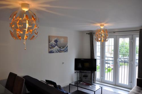 a living room with two chandeliers and a tv at Watford Gemini Hurst in Watford