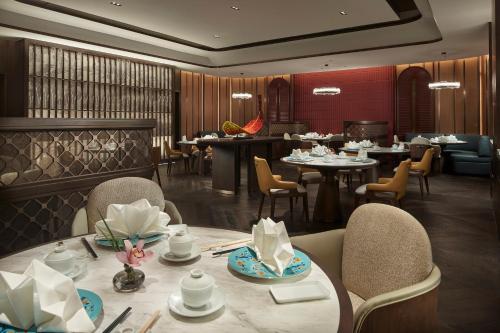 InterContinental Hotels Zhengzhou في تشنغتشو: غرفة طعام مع طاولات وكراسي ومطعم