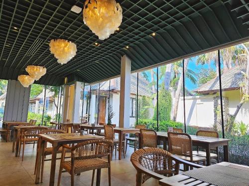a restaurant with wooden tables and chairs and windows at Baan Haad Ngam Boutique Resort in Chaweng